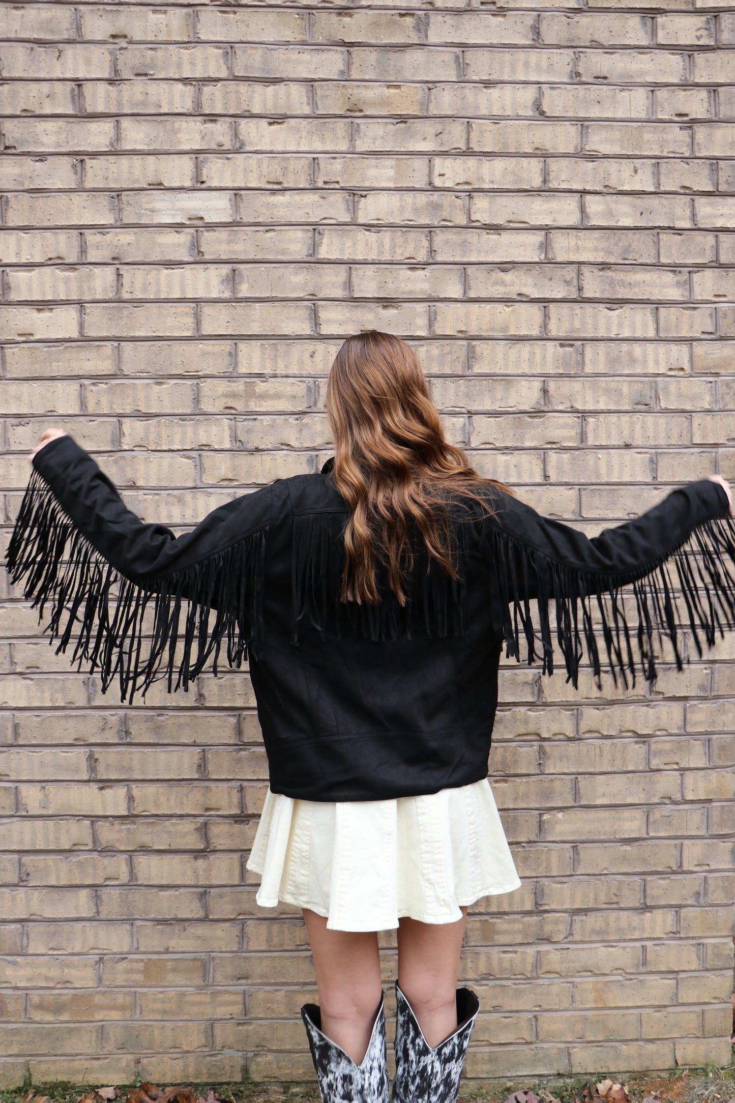 Person wearing a suede fringe black jacket. 