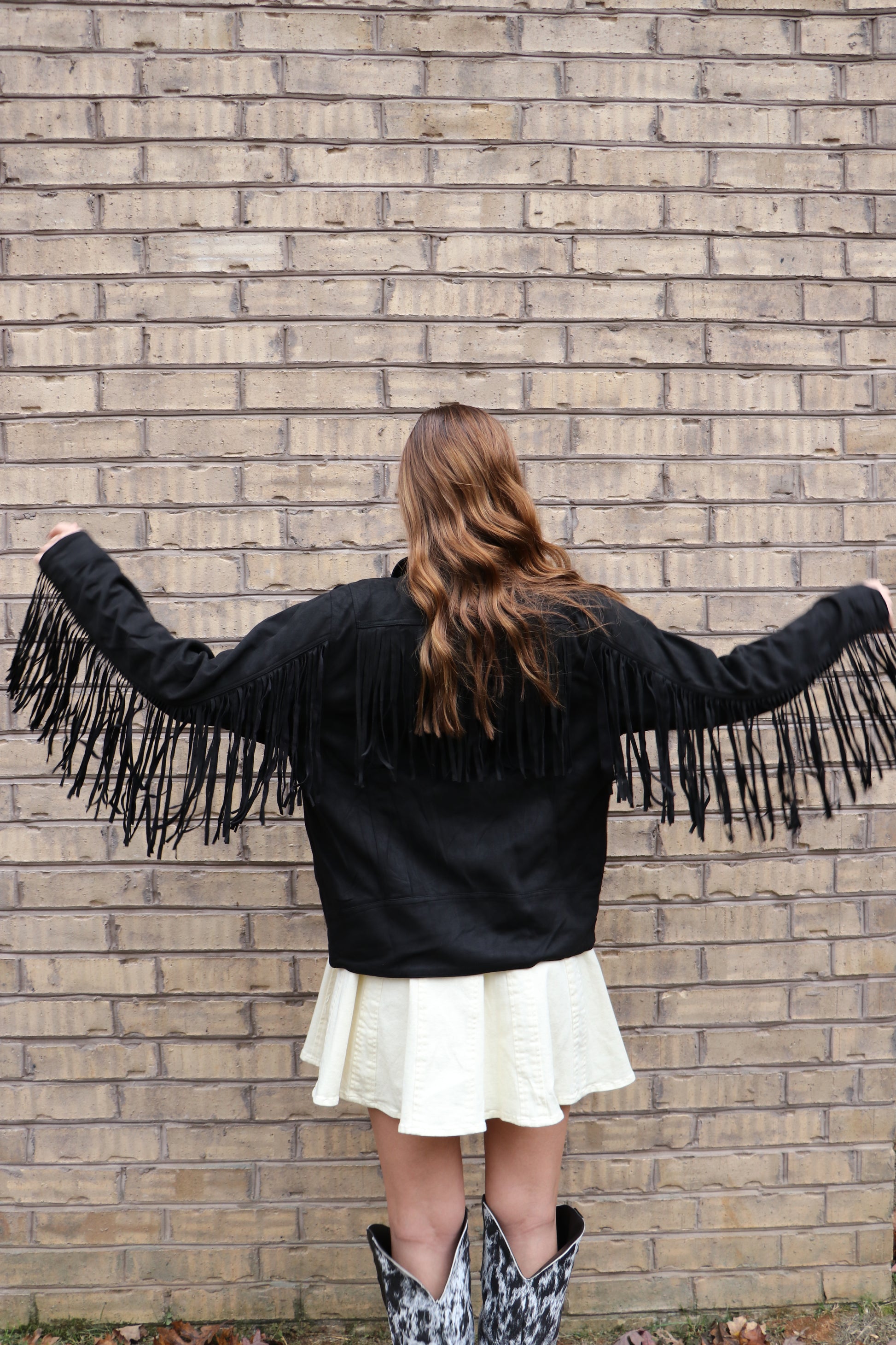 Person wearing a suede fringe black jacket. 