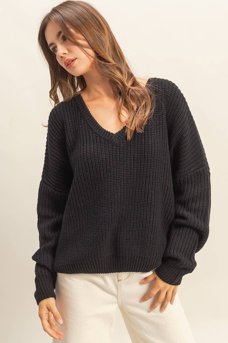 Woman wearing a black oversized V-neck sweater. 