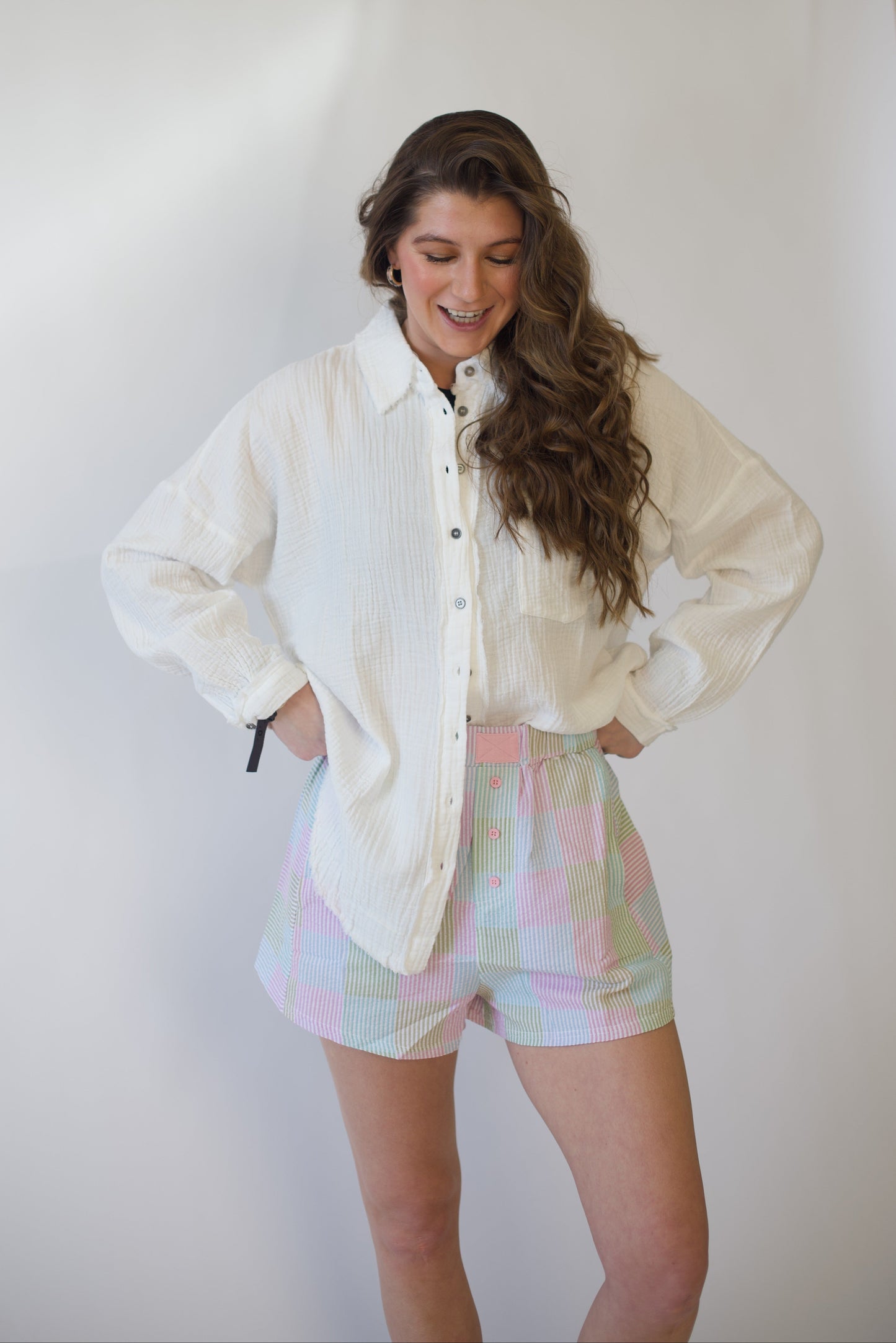 Woman wearing a white shirt and colorful shorts against a plain background