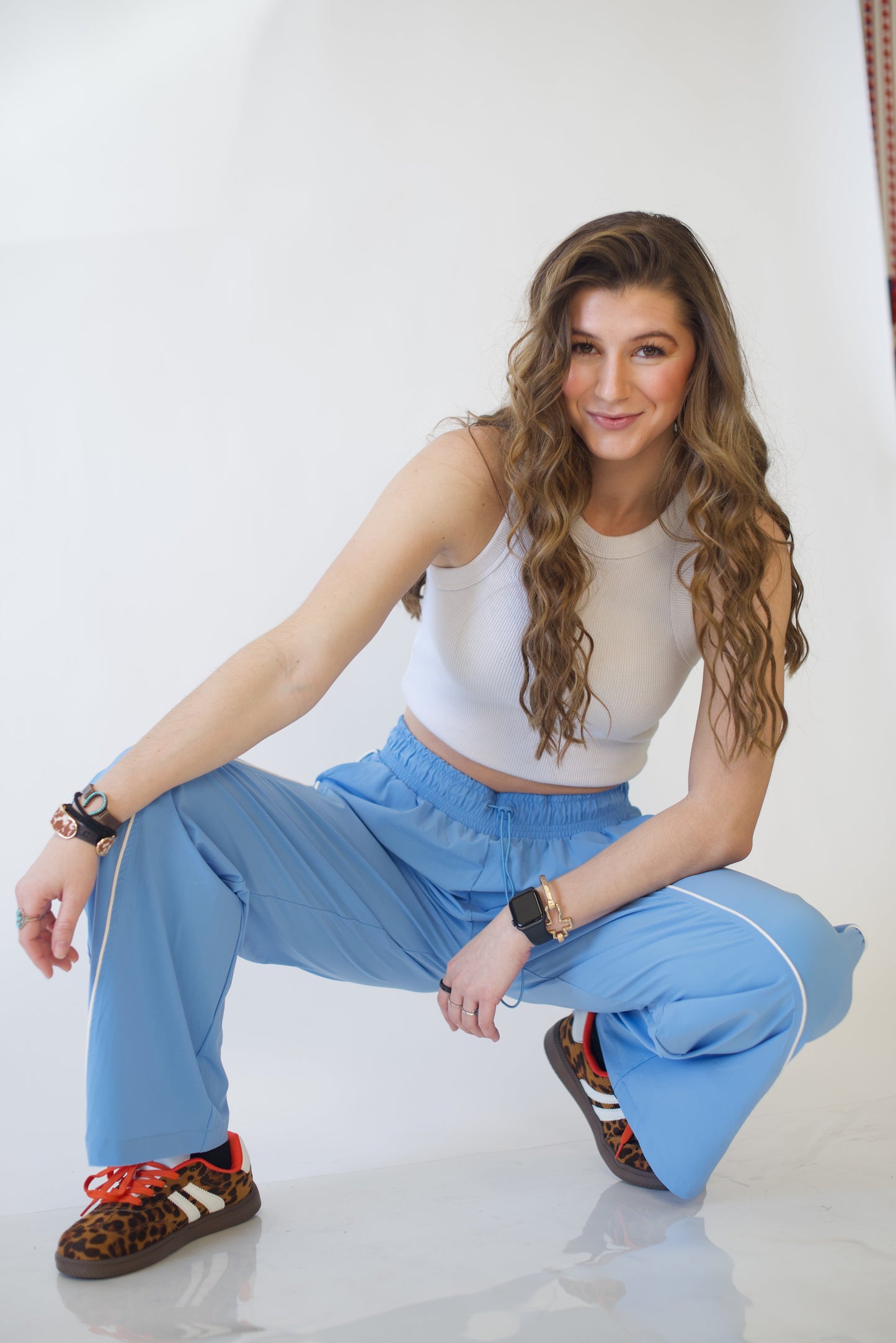 Woman in a white top and blue pants posing on a white floor.