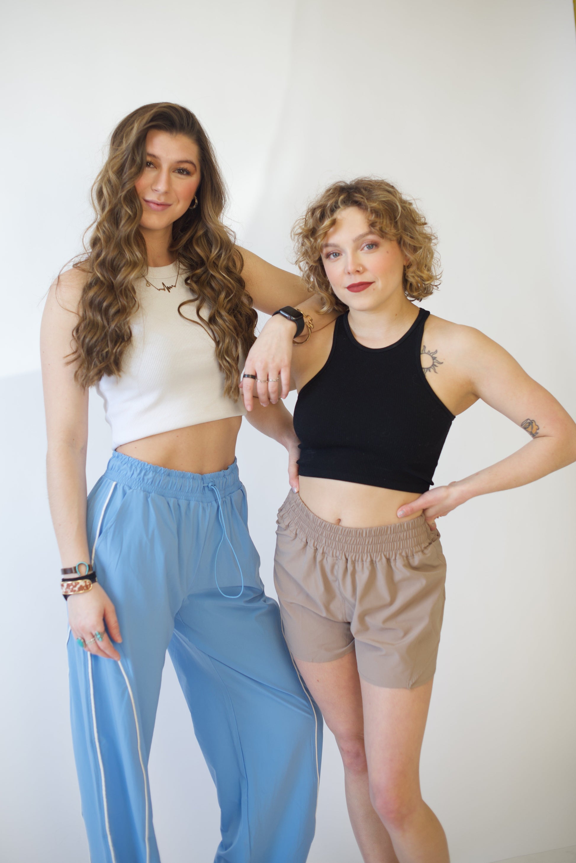 Two women wearing activewear posing together against a white background