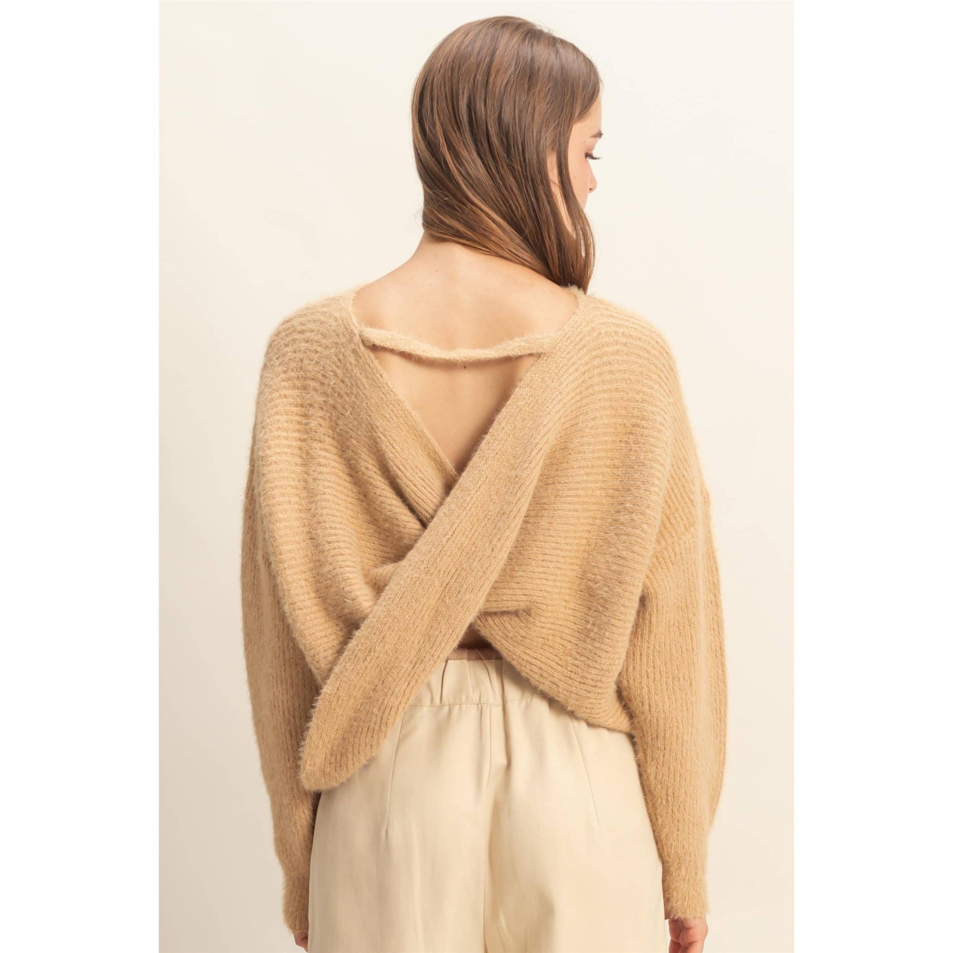 Woman wearing a cross back beige sweater. 